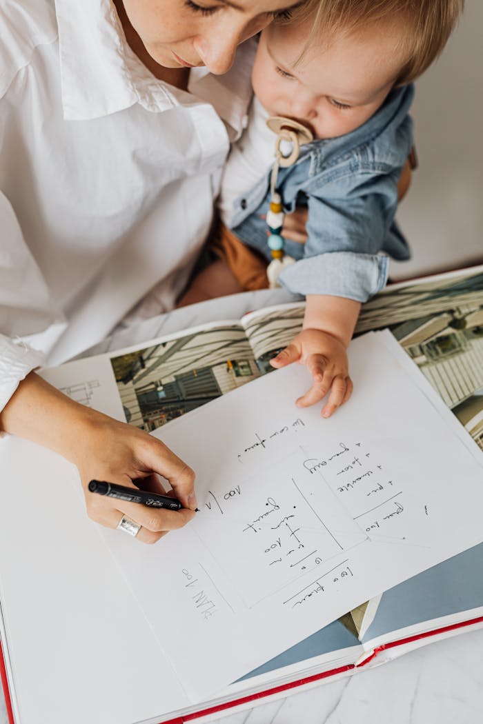 A mother writing while holding her baby in a cozy home office setting, illustrating multitasking.